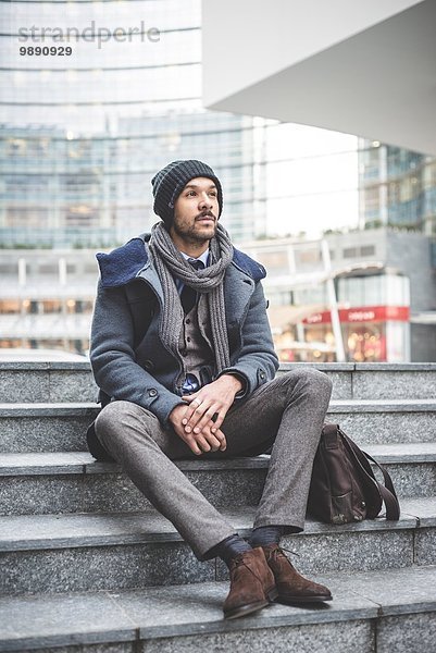 Mittlerer erwachsener Geschäftsmann auf Bürotreppe sitzend