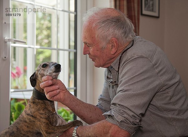 Senior Mann streichelt Haustier Hund