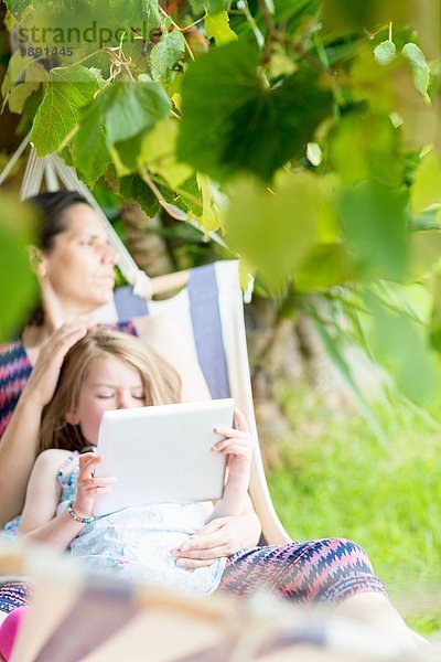 Tochter sitzt auf dem Schoß der Mutter mit einem digitalen Tablett