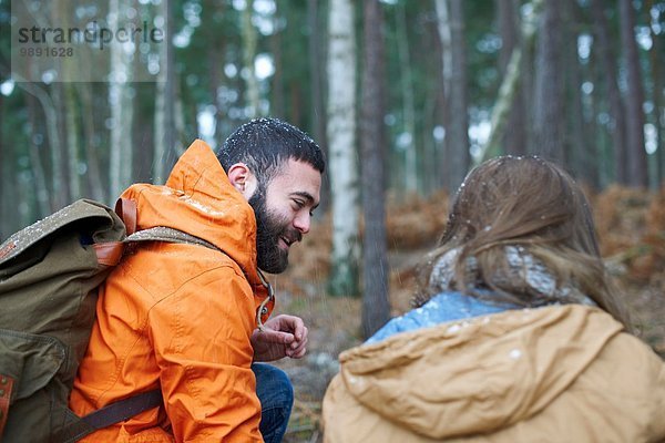 Junges Wanderpaar kauernd im Wald