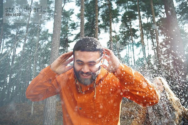 Junge Frau besprüht Freund mit Wasser im Wald