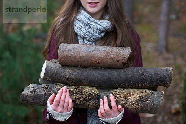 Junge Frau sammelt Baumstämme für Lagerfeuer im Wald