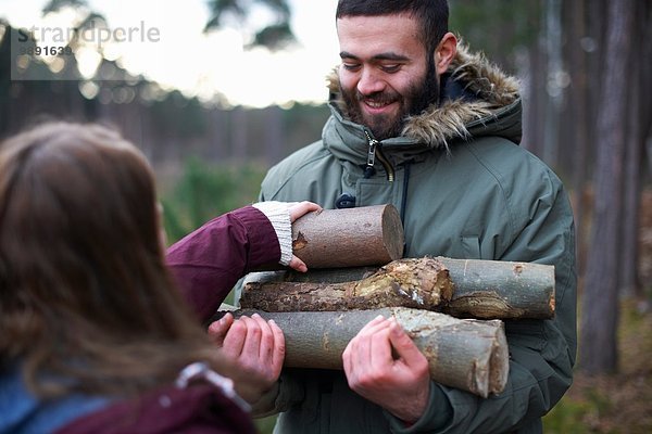 Junges Wanderpaar sammelt Baumstämme für Lagerfeuer im Wald