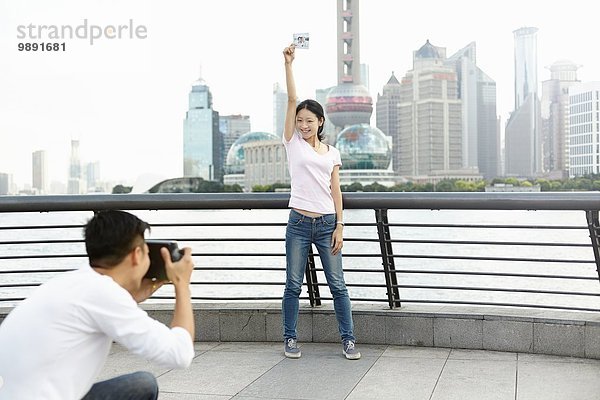 Touristin mit Sofortbildaufnahme für Freund mit Sofortbildkamera  The Bund  Shanghai  China