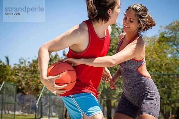 Junges Paar flirtet auf dem Basketballplatz