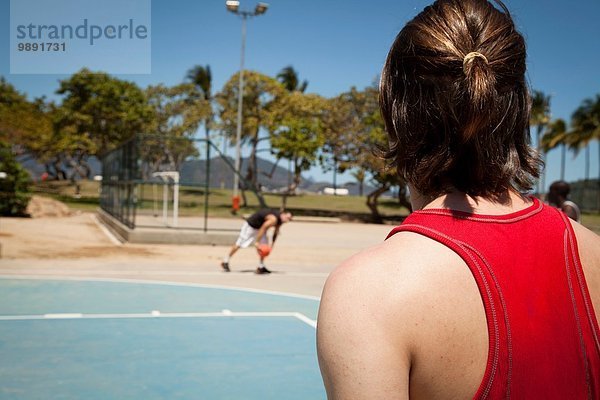 Zwei junge Männer spielen Basketball auf dem Basketballplatz.