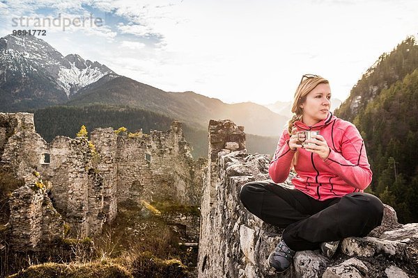 Junge Frau trinkt Kaffee auf der Burgruine Ehrenberg  Reutte  Tirol  Österreich