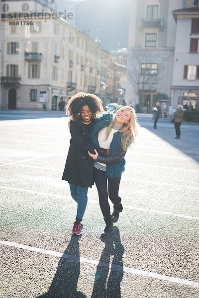 Zwei Freundinnen  die auf dem Marktplatz spazieren gehen und lachen.