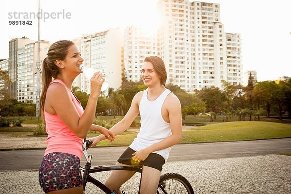 Junges Paar beim Plaudern während der Vorbereitung auf das Radfahren im Park