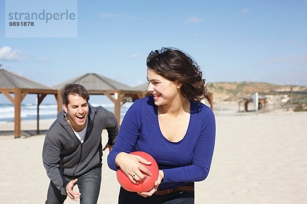 Junges Paar läuft mit Ball am Strand  Tel Aviv  Israel