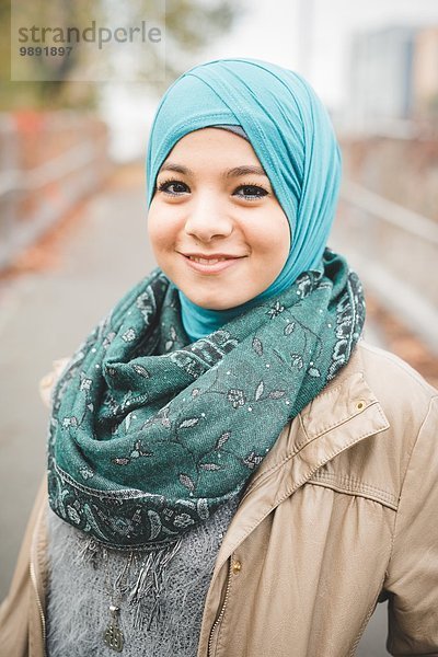 Porträt einer jungen Frau mit türkisfarbenem Hijab auf dem Parkweg