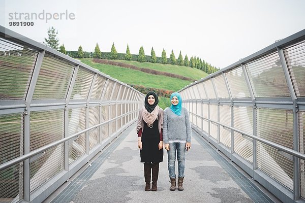 Porträt von zwei jungen Freundinnen auf der Parkfußgängerbrücke