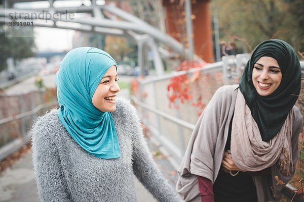 Zwei junge Freundinnen lachen auf dem Parkweg