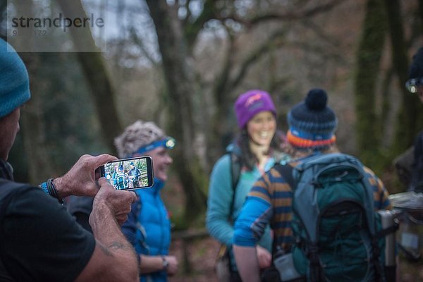 Mann fotografiert Freunde mit Smartphone