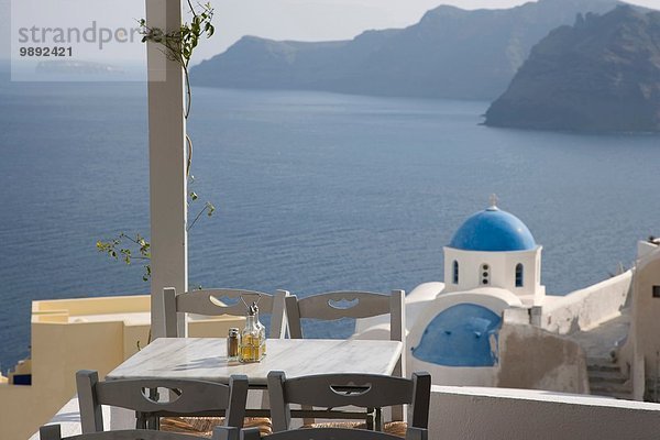 Blick auf Balkonrestaurant und weiß gewaschene Kirche  Oia  Santorini  Kykladen  Griechenland