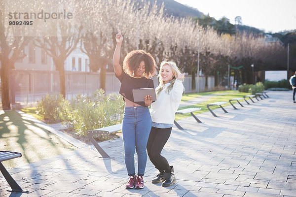 Zwei junge Freundinnen im Park lachend über Digital Tablet  Como  Italien