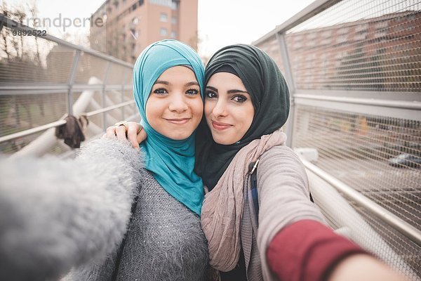 Zwei Freundinnen auf der Fußgängerbrücke nehmen Selfie