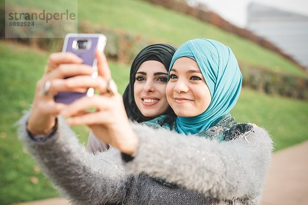 Zwei Freundinnen im Park nehmen Smartphone Selfie