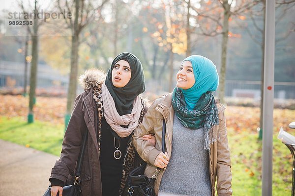Zwei junge Frauen  die beim Spaziergang im Park aufblicken