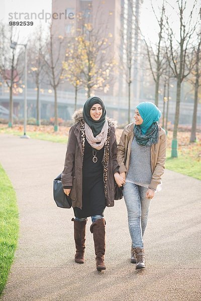 Zwei junge Frauen plaudern beim Bummeln im Park