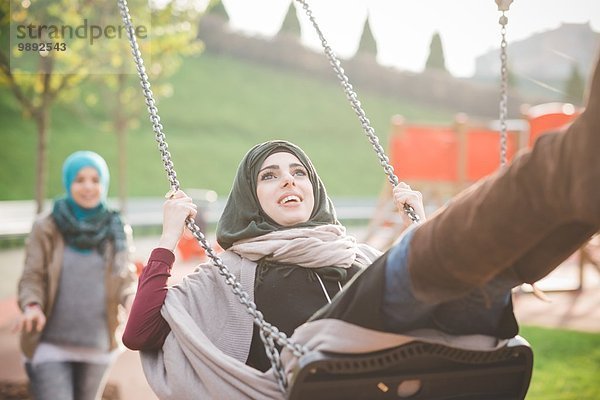 Junge Frauen schwingen auf der Spielplatzschaukel