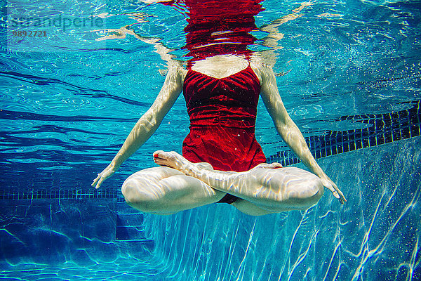 Reife Frau in rotem Kleid  Beine gekreuzt  Unterwasseransicht  niedriger Schnitt