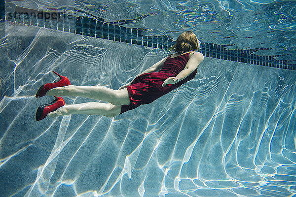 Reife Frau in rotem Kleid und High Heels  schwimmend  Unterwasseransicht
