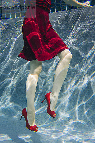 Reife Frau in rotem Kleid und High Heels  Unterwasseransicht  tiefer Schnitt