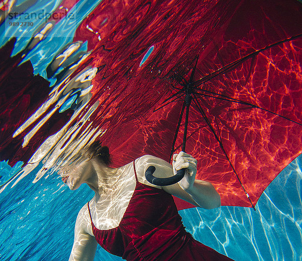 Reife Frau im roten Kleid  mit rotem Regenschirm  Unterwasseransicht  Mittelteil