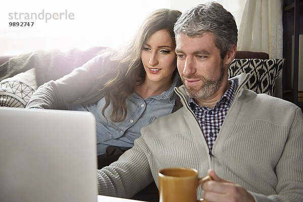 Junges Paar trinkt Kaffee und schaut auf den Laptop