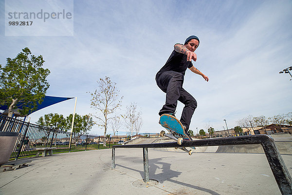 Junger Mann beim Skateboarden auf dem Geländer