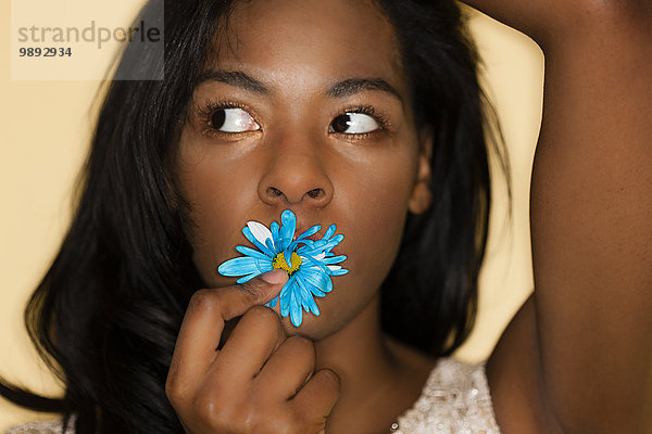 Junge Frau posiert mit Blume im Mund