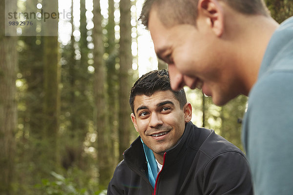 Zwei junge Männer  die zusammen im Wald lachen.