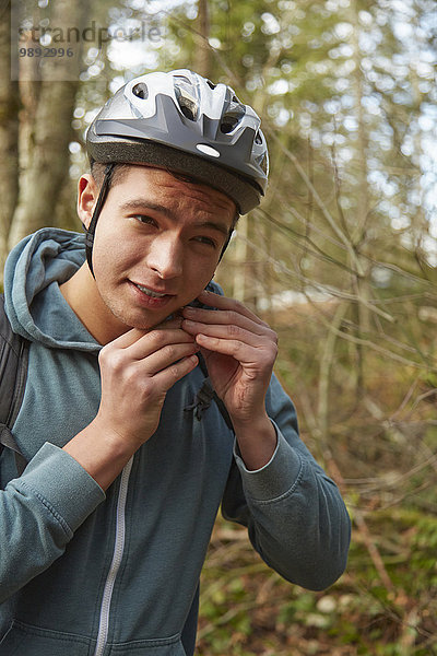 Junger Mann im Wald sichert Fahrradhelm
