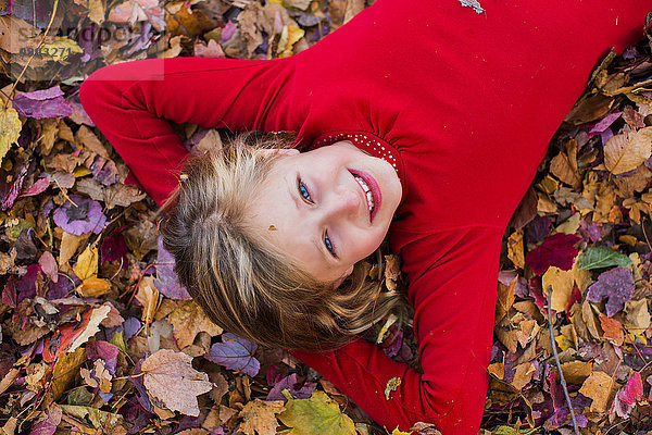Porträt eines jungen Mädchens  in Herbstblättern liegend
