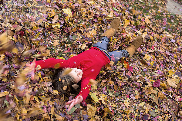 Junges Mädchen spielt im Herbstlaub