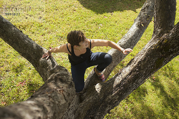 Mittlere erwachsene Frau klettert auf den Baum