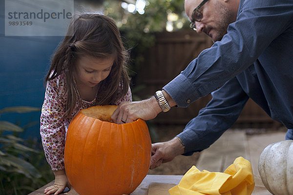 Vater und Tochter schnitzen Kürbis zu Halloween