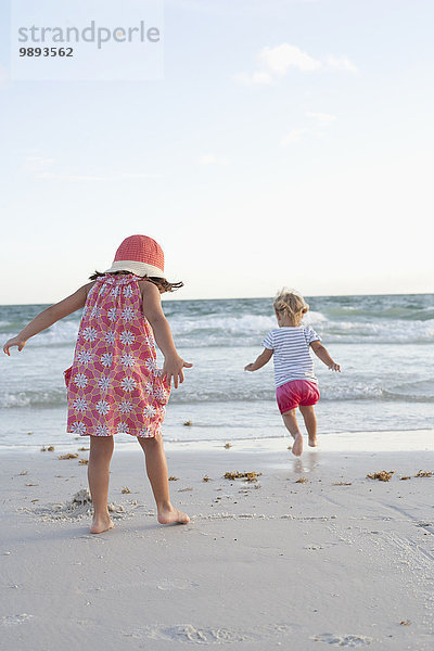 Geschwister erkunden am Strand bei Sonnenuntergang