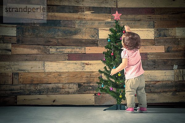Kleines Mädchen schmückt Weihnachtsbaum