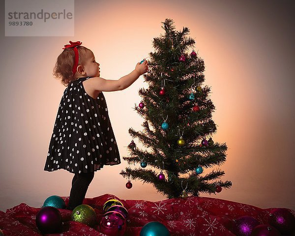 Kleines Mädchen schmückt Weihnachtsbaum