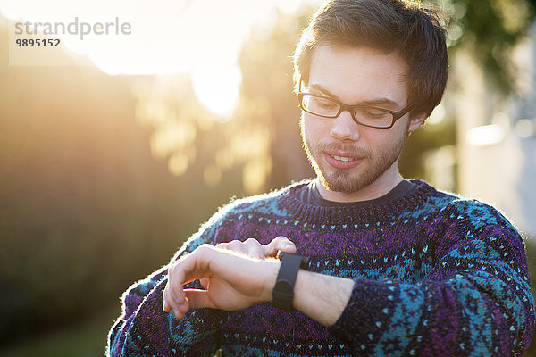 Portrait eines jungen Hipsters mit smartwatch im Gegenlicht