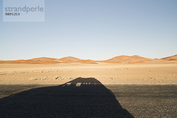 Namibia  Namib Wüste  Namib Naukluft Park  Schatten eines durch Sossusvlei fahrenden Autos