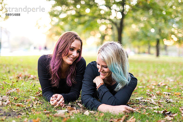 Zwei Freundinnen mit gefärbten Haaren liegen auf einer Wiese.