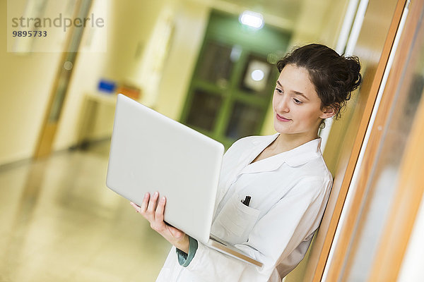 Junger Arzt mit Laptop auf dem Krankenhausboden