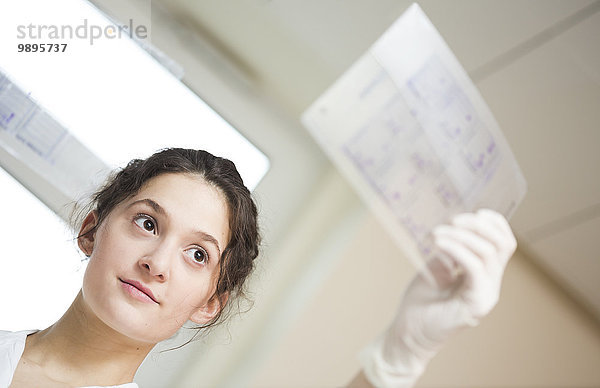 Junge Laborantin auf der Suche nach einem Testblatt