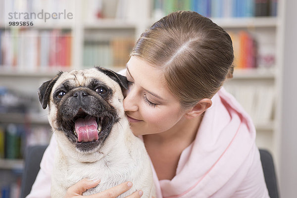 Junge Frau kuschelt mit Mops