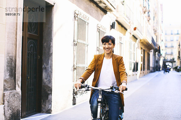 Spanien  Barcelona  lächelnde Frau mit Fahrrad in der Stadt