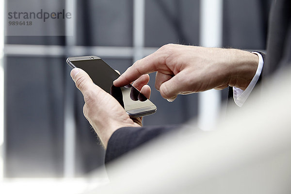 Hände des Geschäftsmannes berühren Bildschirm seines Smartphones