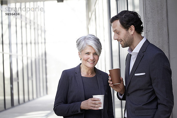 Zwei lächelnde Geschäftsleute mit Kaffee zum Mitnehmen